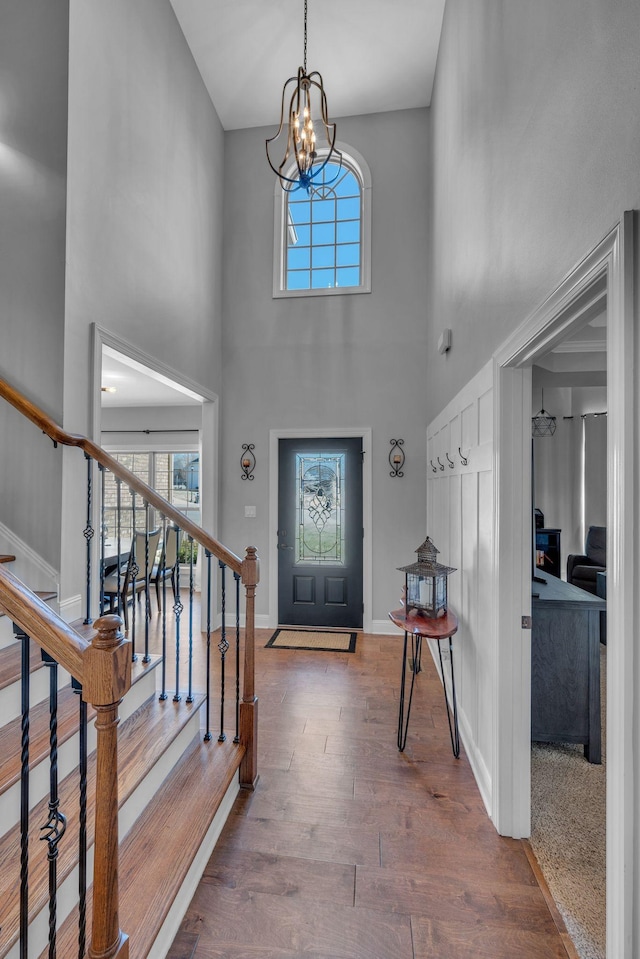 foyer entrance with baseboards, stairway, wood finished floors, an inviting chandelier, and a high ceiling