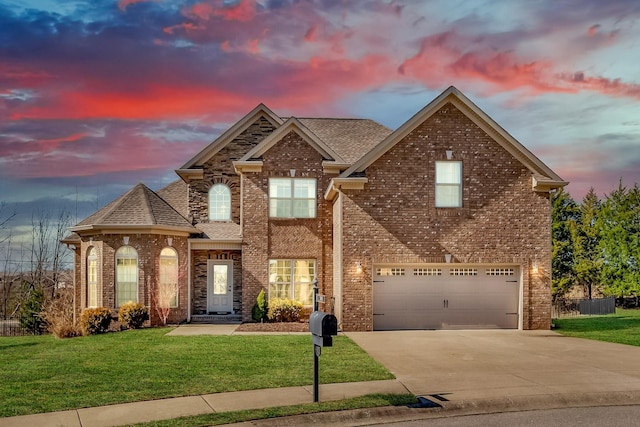 traditional home featuring brick siding, a yard, a shingled roof, concrete driveway, and a garage