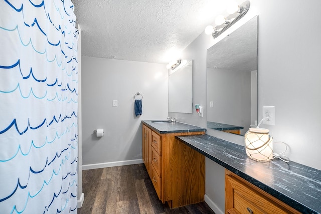 bathroom featuring vanity, a textured ceiling, wood finished floors, a shower with curtain, and baseboards