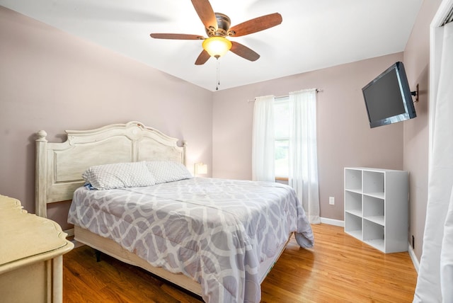 bedroom with a ceiling fan, baseboards, and wood finished floors