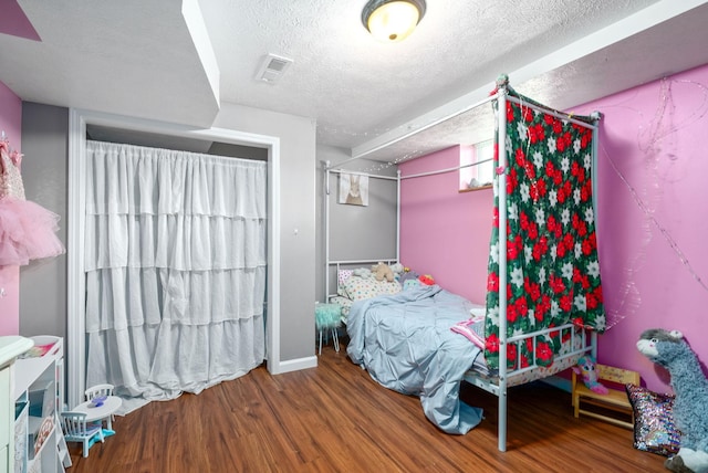 bedroom with a textured ceiling, wood finished floors, and visible vents