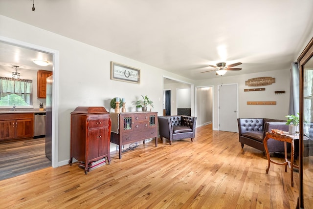 sitting room with light wood-type flooring, ceiling fan, and baseboards