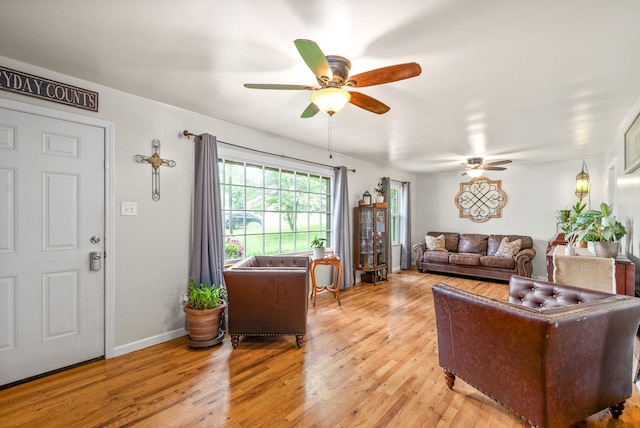 living room with light wood finished floors, a ceiling fan, and baseboards