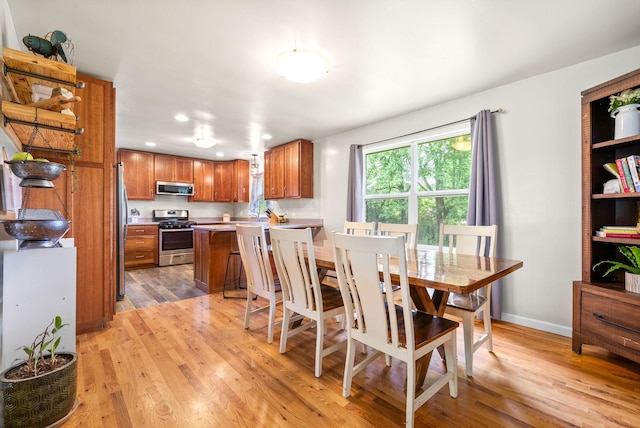 dining room featuring light wood finished floors, baseboards, and recessed lighting