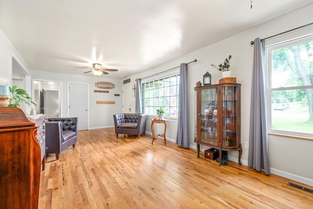 sitting room featuring baseboards, a ceiling fan, visible vents, and light wood-style floors