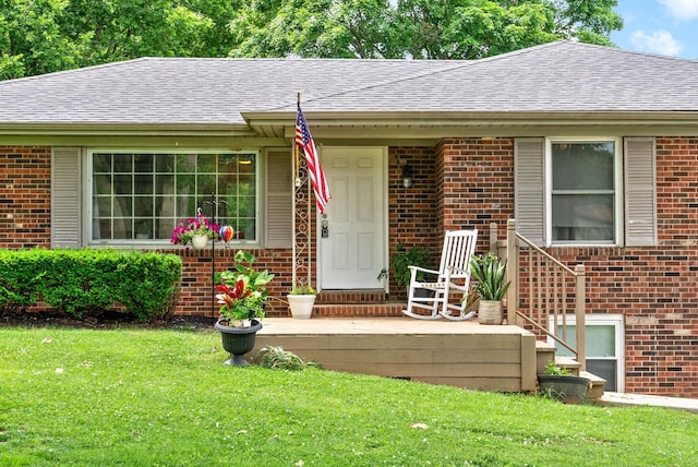 exterior space featuring roof with shingles, a lawn, and brick siding