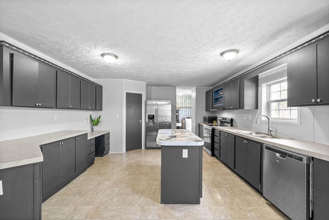 kitchen with a center island, light countertops, appliances with stainless steel finishes, a sink, and a textured ceiling