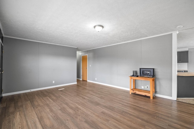 unfurnished room with a textured ceiling, ornamental molding, and wood finished floors