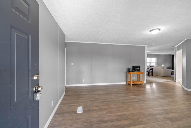 interior space with a textured ceiling, wood finished floors, and baseboards