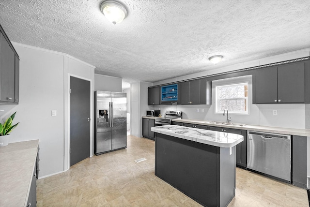 kitchen with light floors, stainless steel appliances, light countertops, a sink, and a kitchen island