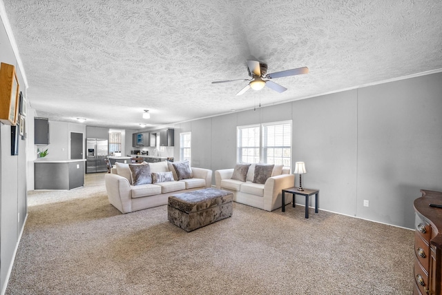 living room featuring a textured ceiling, a ceiling fan, and light colored carpet