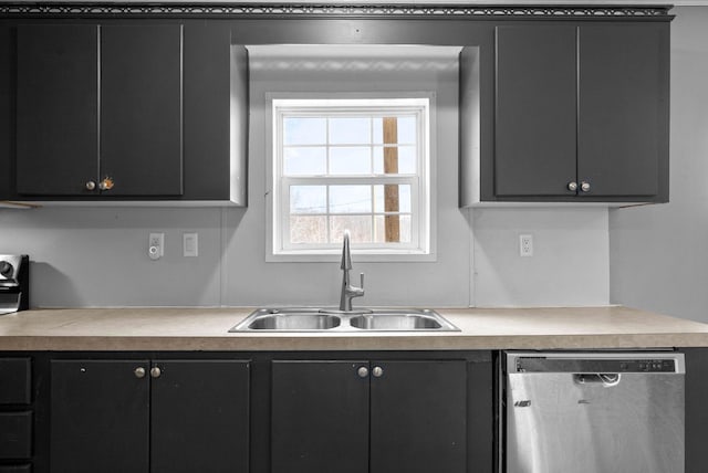 kitchen with light countertops, stainless steel dishwasher, a sink, and dark cabinets