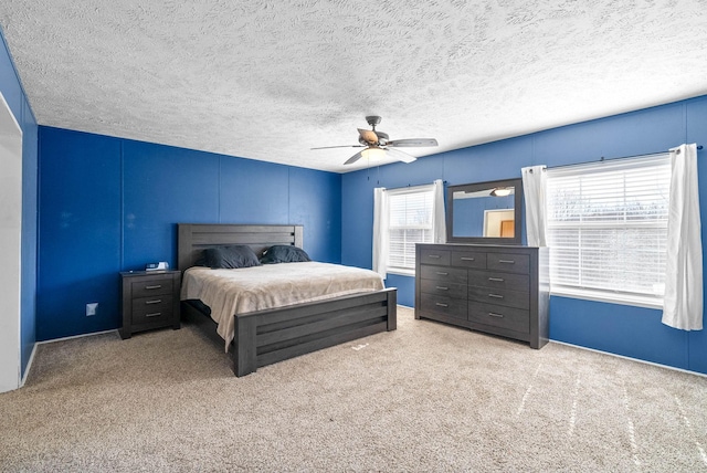 carpeted bedroom featuring ceiling fan and a textured ceiling