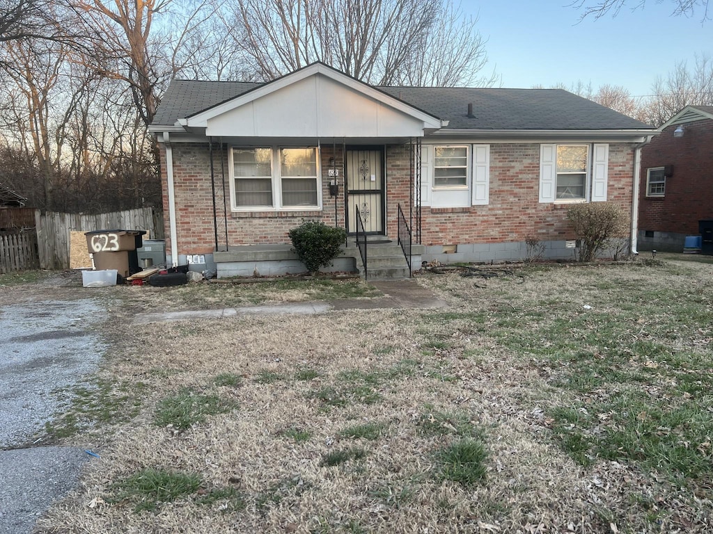 view of front of home featuring crawl space, roof with shingles, fence, and brick siding