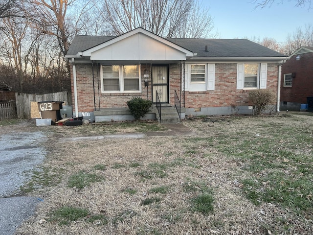 view of front of home featuring crawl space, roof with shingles, fence, and brick siding