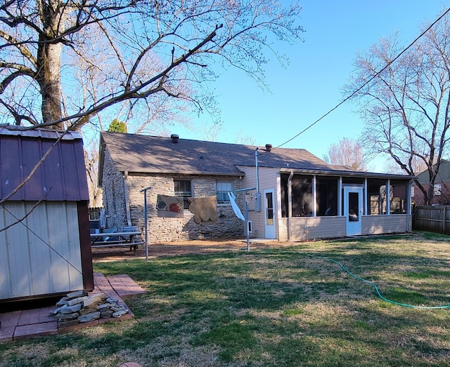 back of house featuring an outbuilding, a sunroom, a yard, and a shed