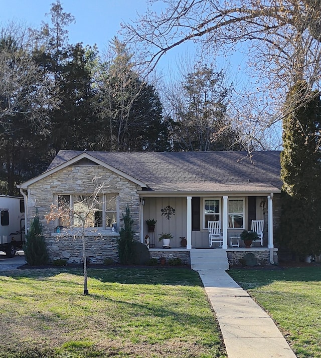 view of front of property with stone siding, covered porch, board and batten siding, and a front yard