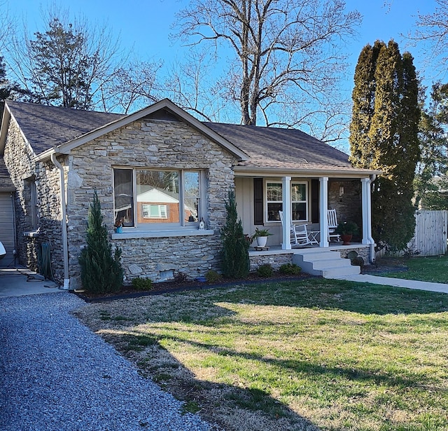 view of front of property featuring covered porch, stone siding, board and batten siding, and a front yard