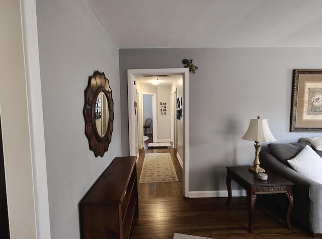 corridor with dark wood-type flooring and baseboards