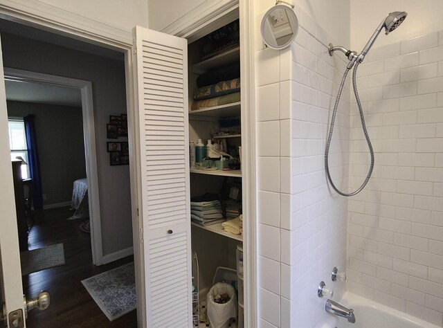 full bathroom featuring baseboards, wood finished floors, and shower / bathtub combination