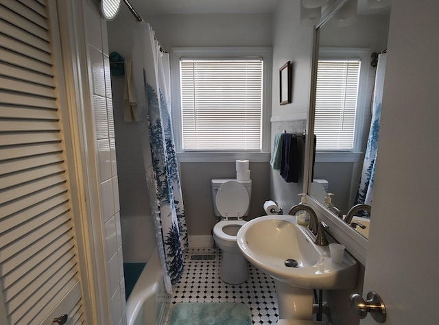 full bathroom featuring visible vents, baseboards, toilet, shower / bath combo with shower curtain, and a sink