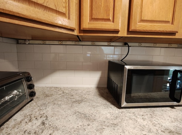 details featuring light countertops, stainless steel microwave, and decorative backsplash