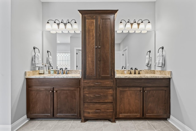 bathroom featuring double vanity, a sink, and baseboards