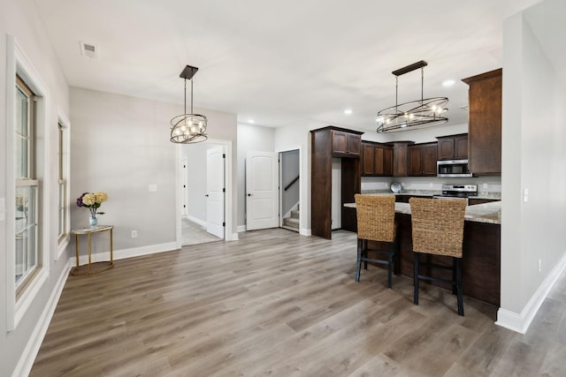 kitchen featuring light wood-type flooring, dark brown cabinetry, baseboards, and stainless steel appliances