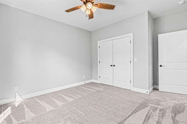 unfurnished bedroom with carpet, a closet, ceiling fan, and baseboards