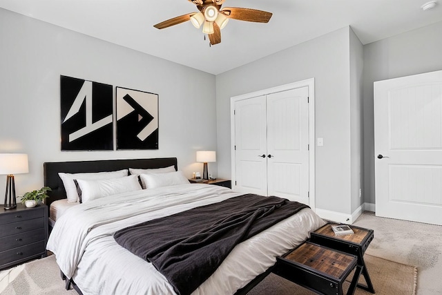 bedroom featuring light carpet, a ceiling fan, baseboards, and a closet