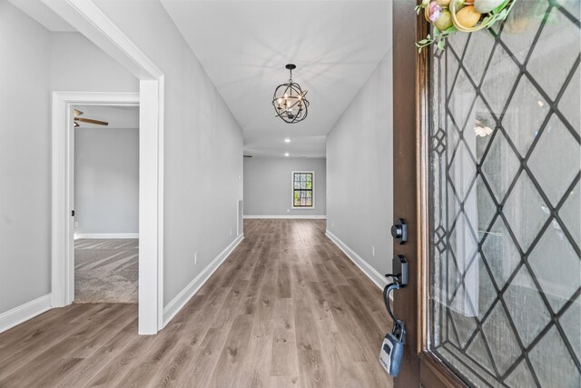 interior space featuring a chandelier, wood finished floors, and baseboards