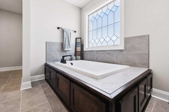 full bath with tile patterned flooring, baseboards, and a bath