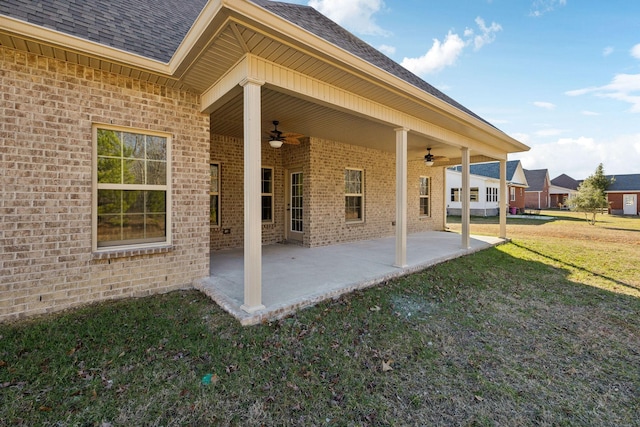 back of property featuring ceiling fan, a patio, brick siding, a shingled roof, and a lawn