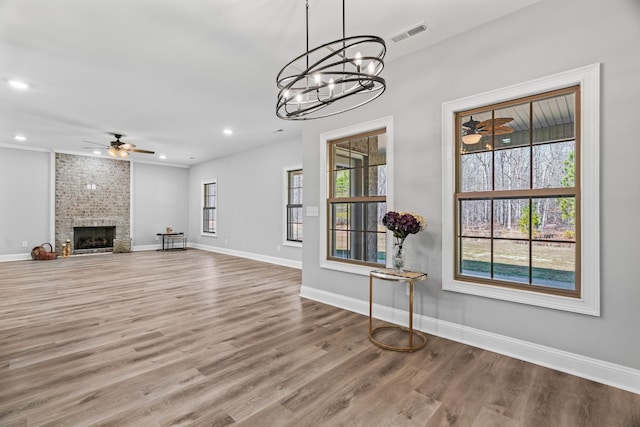 unfurnished living room featuring visible vents, a fireplace, baseboards, and wood finished floors