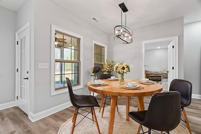 dining area featuring a chandelier, wood finished floors, visible vents, and baseboards