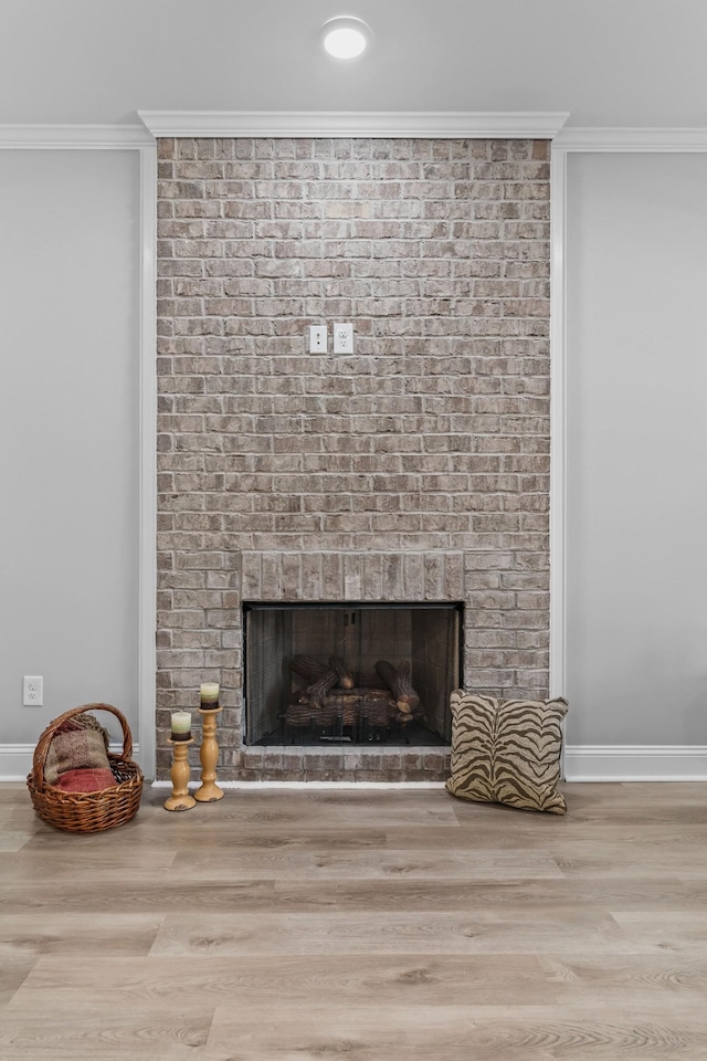 room details with a fireplace, baseboards, crown molding, and wood finished floors