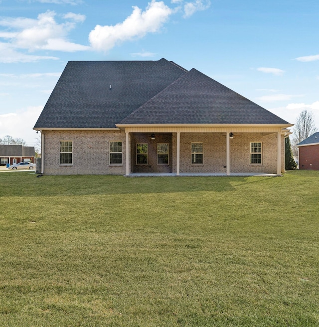 rear view of property featuring a patio area, a shingled roof, a ceiling fan, and a lawn