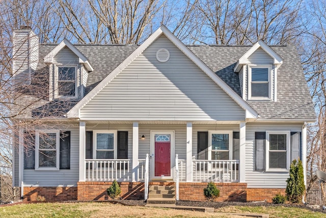 cape cod-style house featuring a porch and roof with shingles