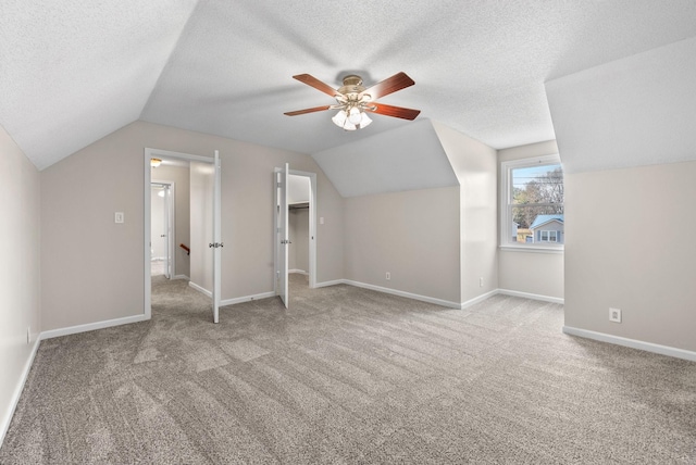 additional living space featuring a textured ceiling, carpet floors, lofted ceiling, and baseboards