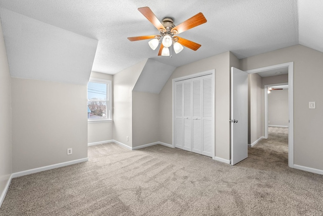 bonus room with baseboards, ceiling fan, vaulted ceiling, a textured ceiling, and carpet flooring