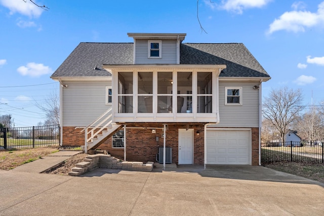 view of front of home with a sunroom, brick siding, fence, and stairs