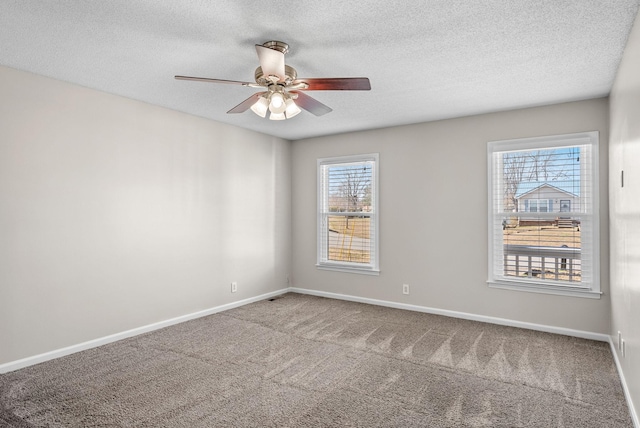 carpeted spare room featuring a textured ceiling, a ceiling fan, and baseboards