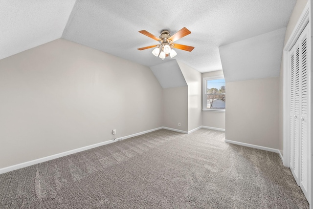 bonus room featuring baseboards, a ceiling fan, lofted ceiling, a textured ceiling, and carpet floors