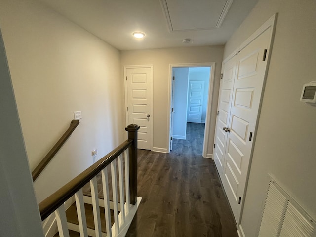 hallway with baseboards, visible vents, dark wood finished floors, and an upstairs landing