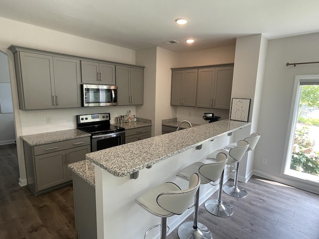 kitchen with light stone counters, appliances with stainless steel finishes, gray cabinets, and visible vents