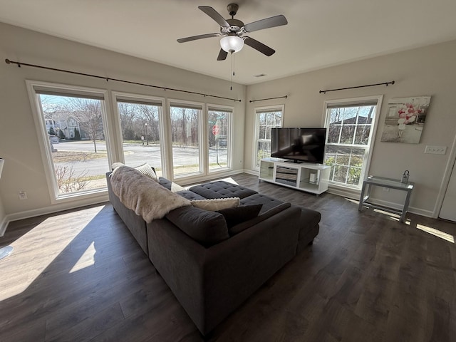 living room featuring dark wood-style floors, visible vents, baseboards, and a ceiling fan