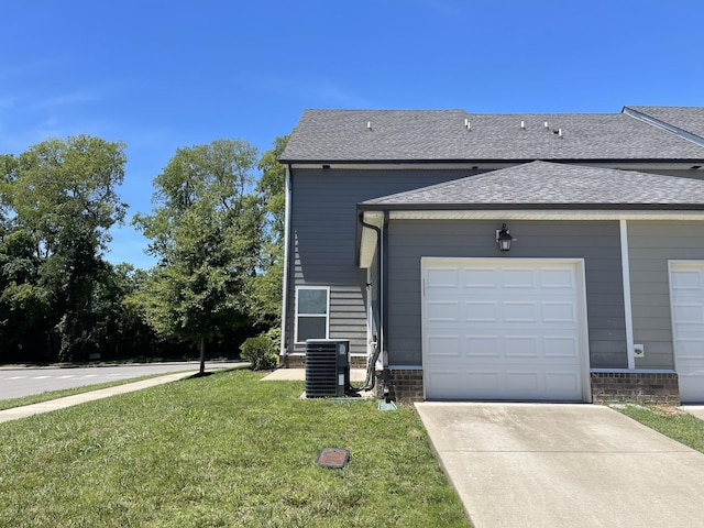 view of property exterior with central AC unit, concrete driveway, roof with shingles, an attached garage, and a yard