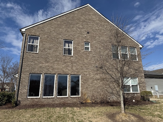 back of property featuring brick siding and a lawn