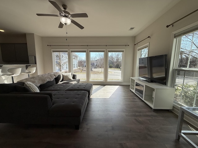 living area featuring dark wood-style flooring, plenty of natural light, visible vents, and a ceiling fan