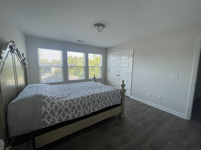 bedroom featuring baseboards, visible vents, dark wood finished floors, and a closet